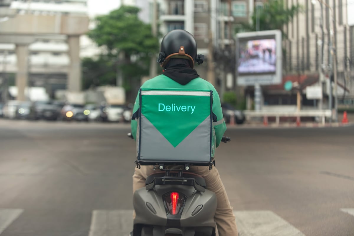 Motoboy delivery com bebidas saindo em alta velocidade